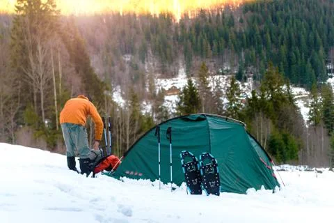 Man gets something out of  backpack near  tent on snow Stock Photos