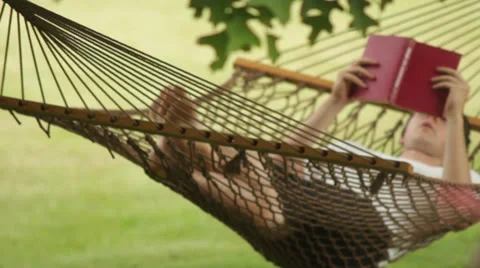 Man getting into and reading in a hammock Vídeo Stock 24701556
