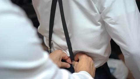 Man getting help with clipping on suspenders Stock Footage 87296532
