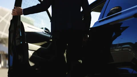 Man getting into his car and preparing to drive. Businessman dressed in business Stock Footage 194754666