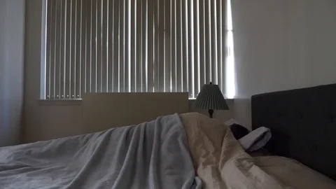 Man getting out of bed letting the sunshine i n Stock Footage 113476256