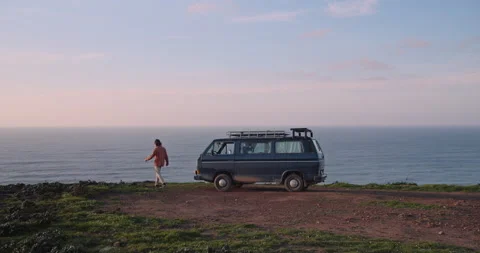 Man Getting Out of Vintage Van Parked on Cliff, Ocean and Sunset Behind Stock Footage 238950768