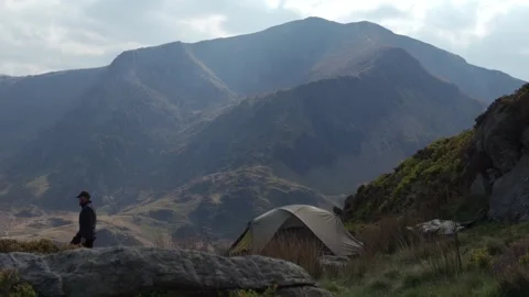 A man getting out of a wild camping tent in an amazing mountain landscape Video stock 251650718