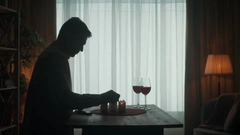 The man is getting ready for a date. The dark silhouette of a man lights candles Stock Footage 245458693
