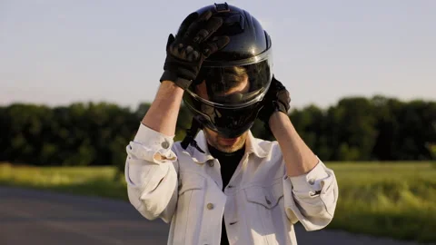 Man getting ready for a motorcycle ride, putting on black helmet. Scene captures Stock Footage 283889785