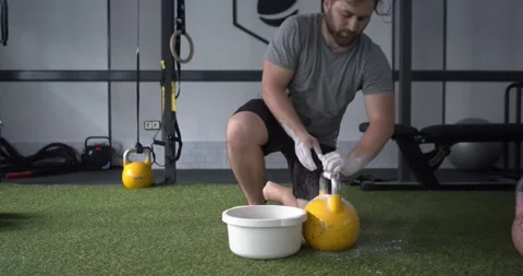 Man getting ready by smearing his hands in magnesium to lift a kettlebell Stock Footage 162407281