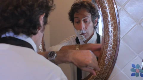 A man getting ready for work checks his watch and runs out with a half a beard Stock Footage 67399786