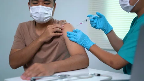 A man is getting a shot and a nurse is administering it Stock Footage 291154745