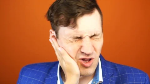 Man getting slapped on orange background. Unhappy scared man getting slapped Stock Footage 112378953