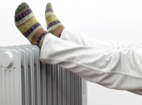 A Man Getting warm in cold winter days. Two feet placed on a heater for warmt Stock Photos