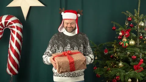 A man with a gift box in his hands near the christmas tree Stock Footage 167583924