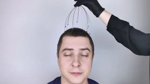 A man is given a head massage with a capillary massager in the salon. The client Stock Footage 147191104