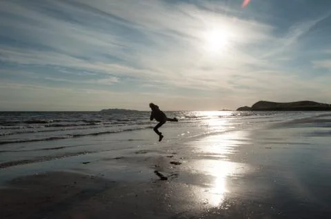 A man gives a kick while jumping on the beach at sunrise Stock Photos