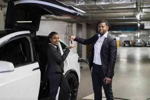 Man giving e-car keys to customer in underground parking 스톡 사진