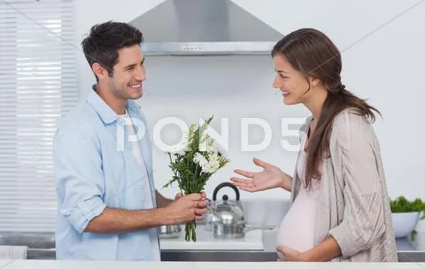 Man giving flowers to his pregnant partner Stock Photos