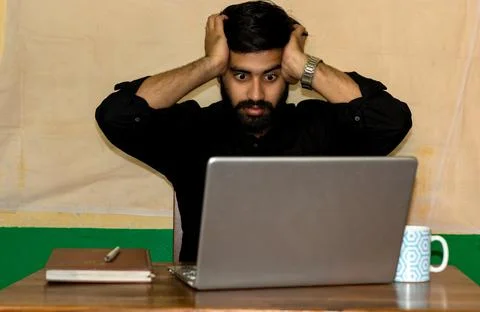 A man giving stressed expression looking at laptop screen Stock Photos