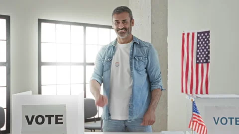 Man giving thumbs up beside vote booth and clear ballot box wearing denim s.. Stock Footage 337372260