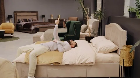 Man giving thumbs up testing bed in furniture store Stock Footage 322550158