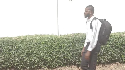 Man in glasses and backpack walks from right to left across the screen Stock Footage 292534403