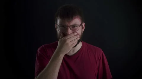 A man with glasses and a beard laughs on a black background Vidéo 169667813