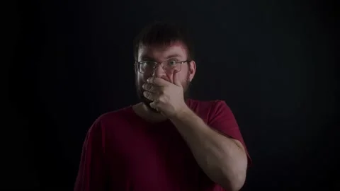 A man with glasses and a beard was frightened on a black background. Stockbeeldmateriaal 169667702