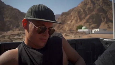 Man in glasses and cap rides in the back of the car slow motion Stock Footage 74268027