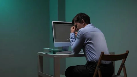 Man in glasses and light blue shirt intently studying a computer screen in a Stock Footage 344605378