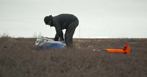 Man in glasses assembles kayak pumps up balloons 스톡 동영상 197059877