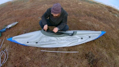 Man in glasses assembles kayak putting reinforcing elements Stock Footage 123696776