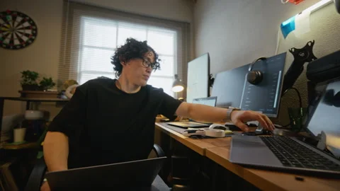 Man with Glasses Coding Software on Multiple Laptops Stock Footage 338424394