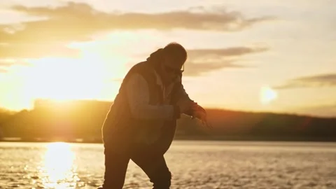 A man with glasses dancing against the backdrop of the setting sun and sky Stock Footage 164915160
