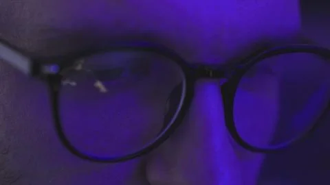 Man with glasses in the dark looking at computer screen, watching dj show online Stock Photos
