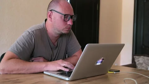 Man with glasses diligently solves difficult task while working on laptop. Stock Footage 243580370