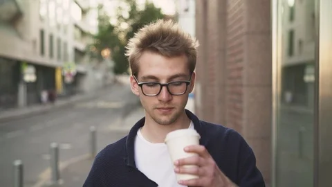 Man in glasses drinking coffee and looking at smartphone 스톡 동영상 97909548