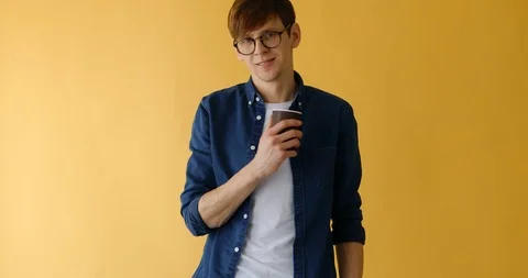 Man with glasses, drinking coffee, on a yellow background Stock Footage 125222188