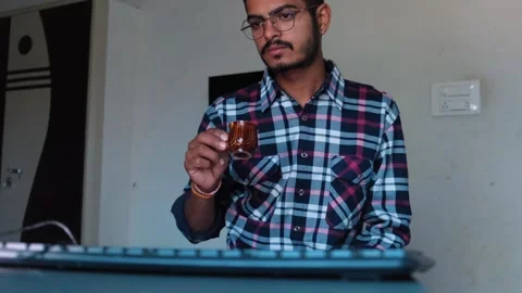 Man with glasses drinking tea or coffee while working at a computer desk Stock Footage 329922009