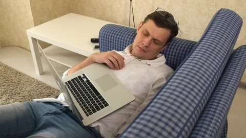 The man in glasses fell asleep while working in the laptop on his couch and Video stock 86174495