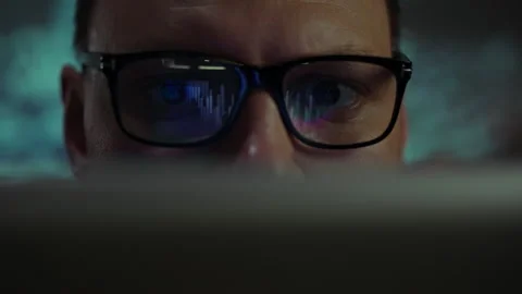 Man with glasses focused on computer screen while analyzing data late at nig Stock Footage 295890048
