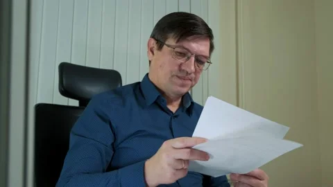 A man with glasses, with a frustrated look, throws the documents on the table Stock Footage 150453110