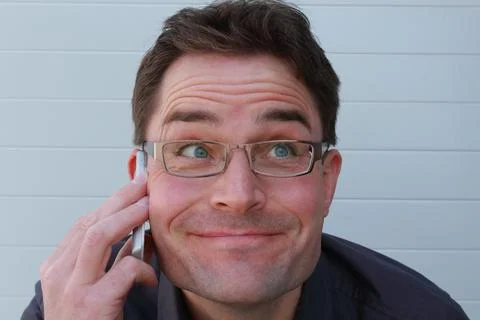 Man with glasses funny grimace while phone call Stock Photos
