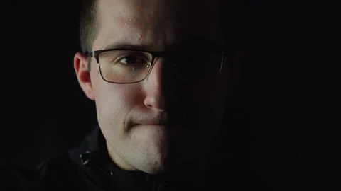 Man with glasses looking at the camera in dim light Stock Footage 142531351