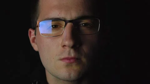 A man with glasses looking at the camera under dim lighting Video stock 142923012