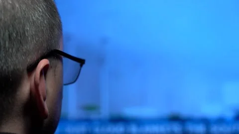 A Man in Glasses is Looking at a Large Screen With a Very Fast News Feed Stock Footage 146784774