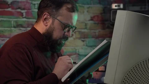Man With Glasses Looking at Paper Documents in Front of Desktop Computer From Stock Footage 305821788