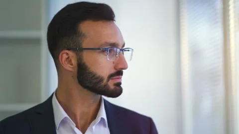 The man in glasses looking to the window through blinds Stock Footage 100743678