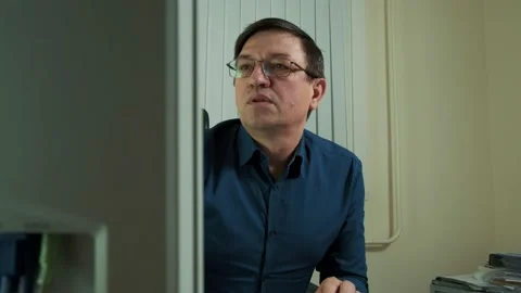 A man with glasses in the office, leaned over the computer Stock Footage 149075369