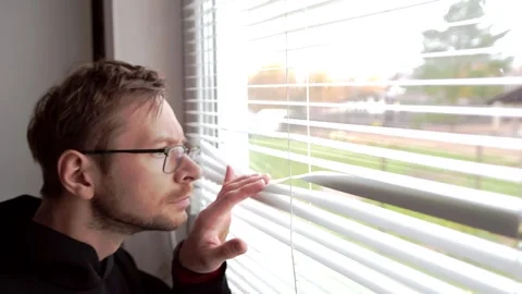 Man in glasses peeking through window blinds. Stock Footage 320022309