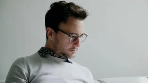 Man with glasses reading book and drinking from tea cup Stock Footage 130637906