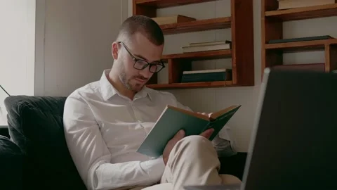 A man with glasses reading a book in a cafe Stock Footage 159904779