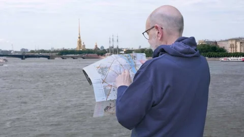 Man With Glasses Reading a Map by Riverfront, Saint Petersburg, Russia Stock Footage 329906250